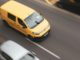 a yellow car and a white car on a road
